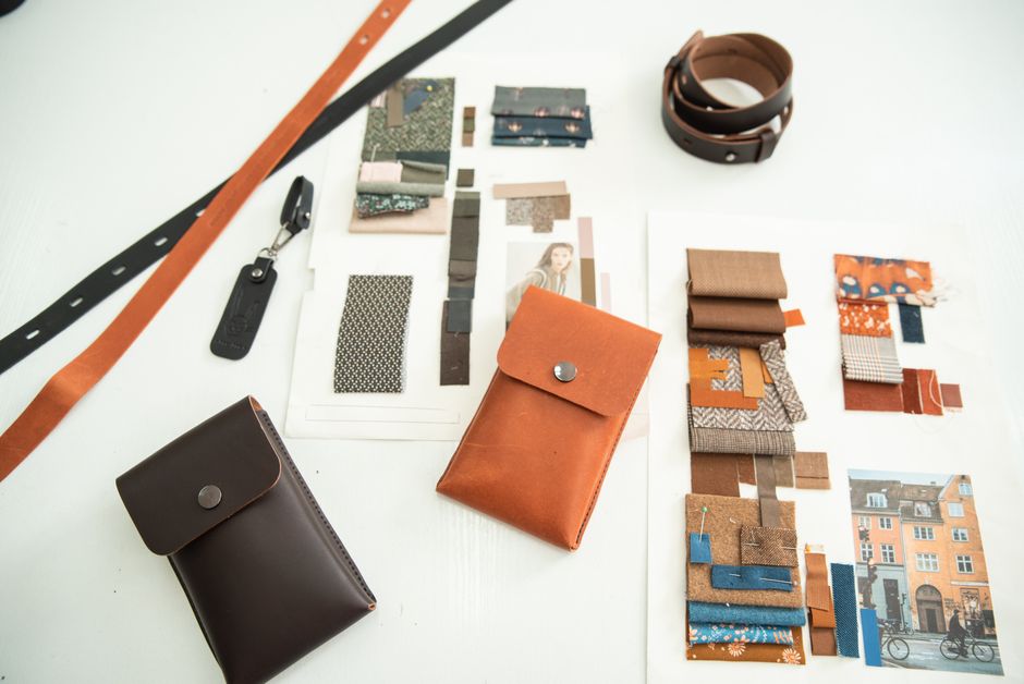 A modern workspace showcasing leather accessories and fabric moodboards for fashion design inspiration.